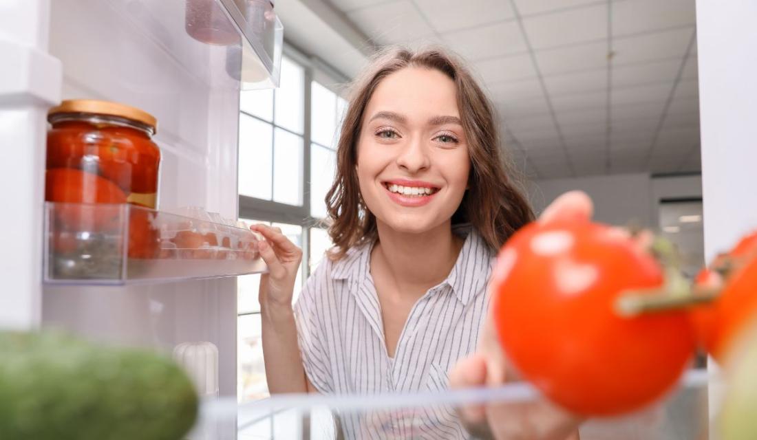 Frau öffnet den Kühlschrank