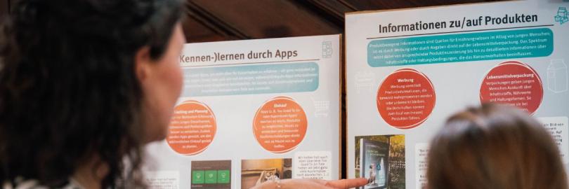 Personen schauen sich ein Aufklärungsplakat an.